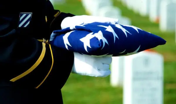 soldier with folded flag at funeral - basic military funeral honors