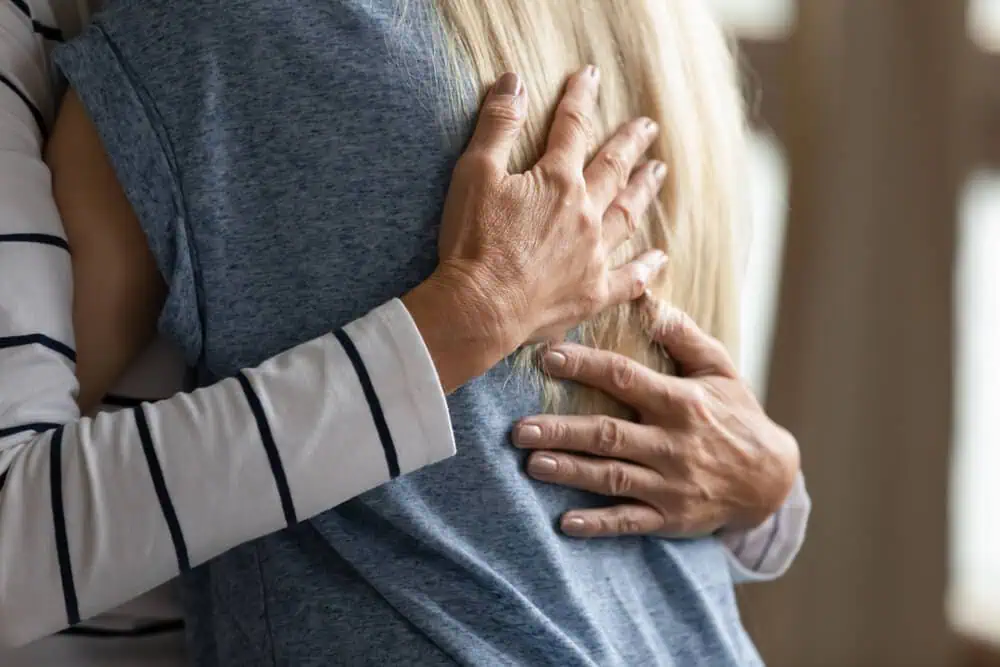 Two individuals embracing while discussing green burial options in Alabama; one wearing a striped shirt, the other in a blue top, representing thoughtful conversations about cremations, funerals, and pre-planning services.